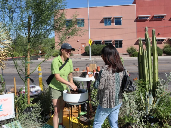 A student assists a community member with potting a succulent