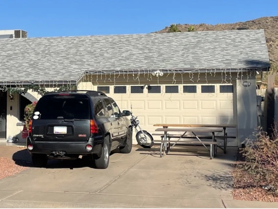 An SUV, motorcycle, and picnic table in the driveway of a single family home with two-car garage.