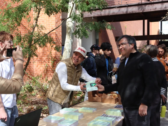 Student poses with a faculty member picking up an issue of the About Journal. 