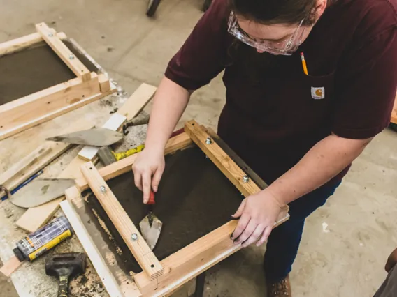 A student smoothing out concrete in the concrete lab at the college of architecture, planning and landscape architecture