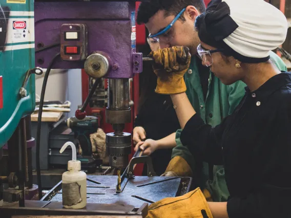 A CAPLA student using a drill press in the materials lab at the college of architecture, planning and landscape architecture at the university of arizona