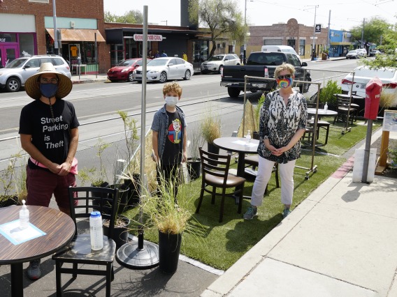 Three visitors stand in the temporary Parking Day parklet on Tucson's Fourth Avenue