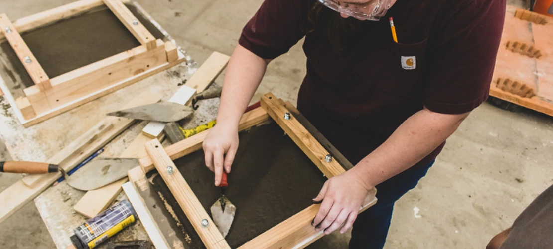 A student smoothing out concrete in the concrete lab at the college of architecture, planning and landscape architecture