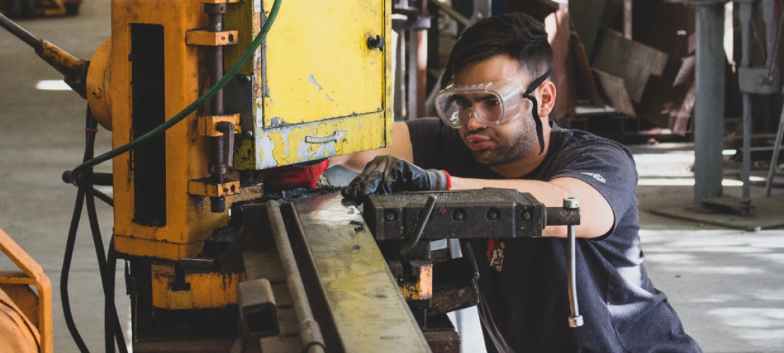 A photo of a CAPLA student cutting a piece of metal for an architecture structure in the materials lab at the college of architecture, planning and landscape architecture
