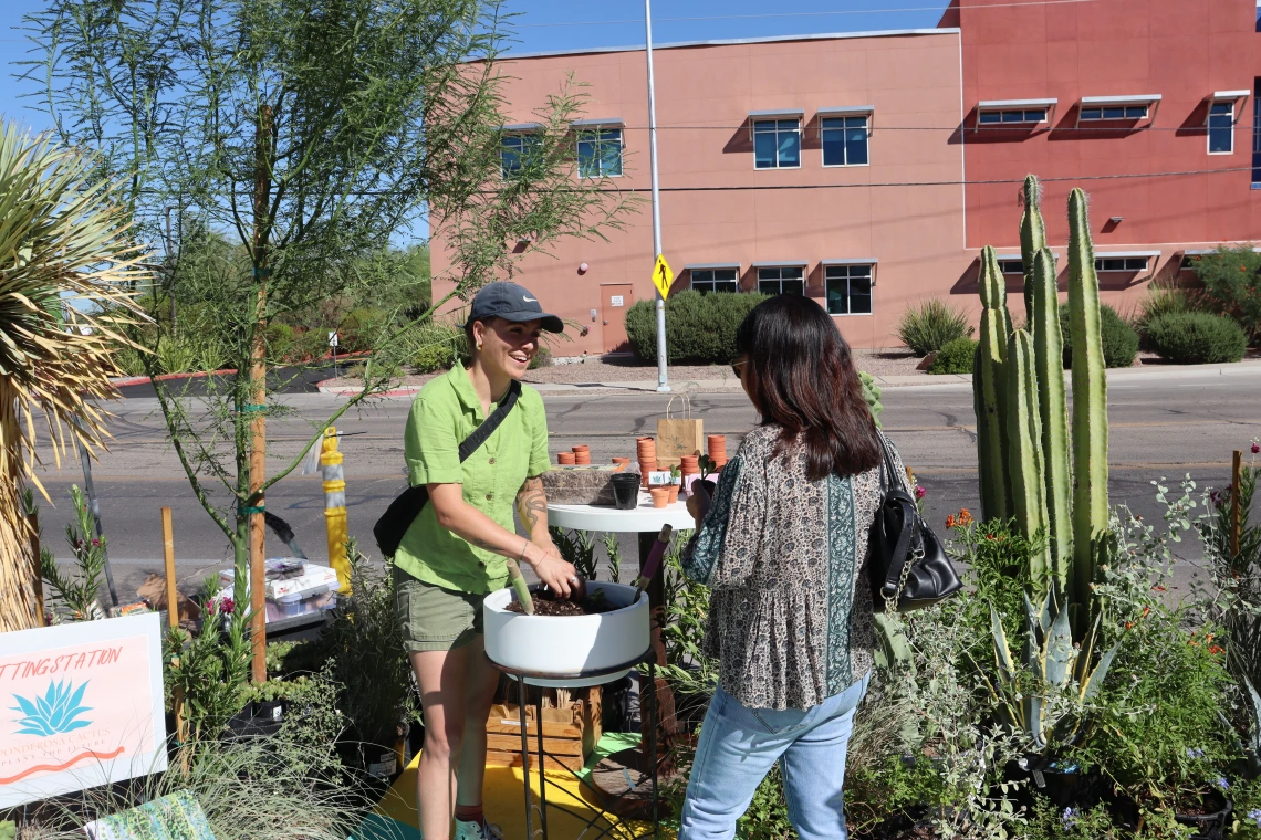 A student assists a community member with potting a succulent