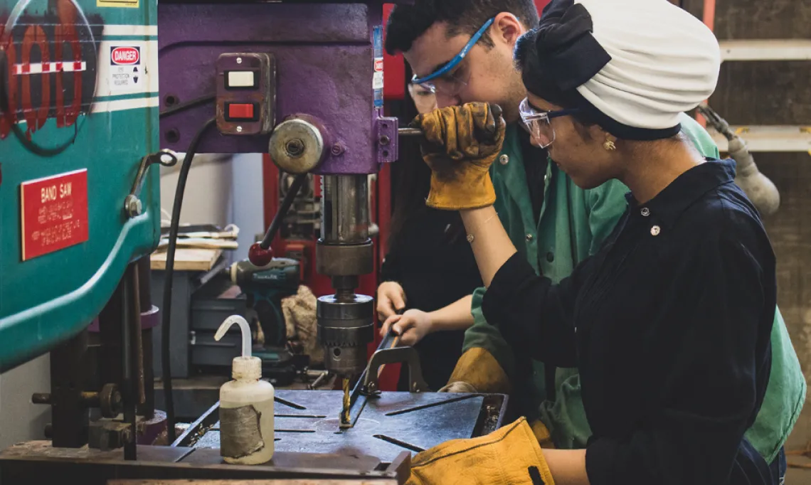 A CAPLA student using a drill press in the materials lab at the college of architecture, planning and landscape architecture at the university of arizona