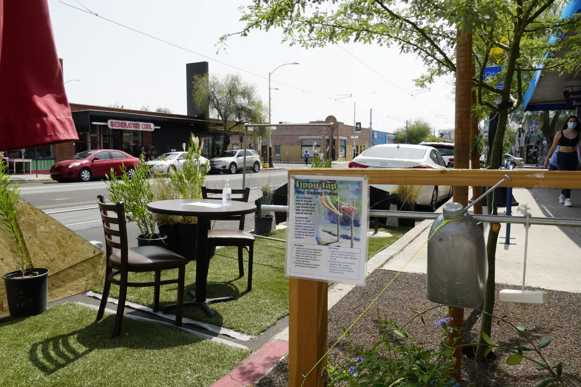 Artificial turf, tables and chairs, and a hand washing station in the Parking Day installation.