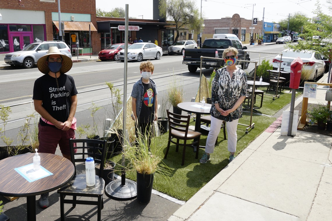 Three visitors stand in the temporary Parking Day parklet on Tucson's Fourth Avenue