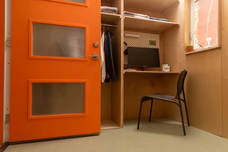 A photo of the mini shelter interior showing a desk and closet.